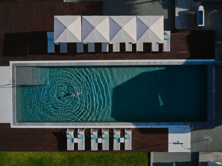 Vista aérea de una piscina con sillas de descanso y sombrillas.