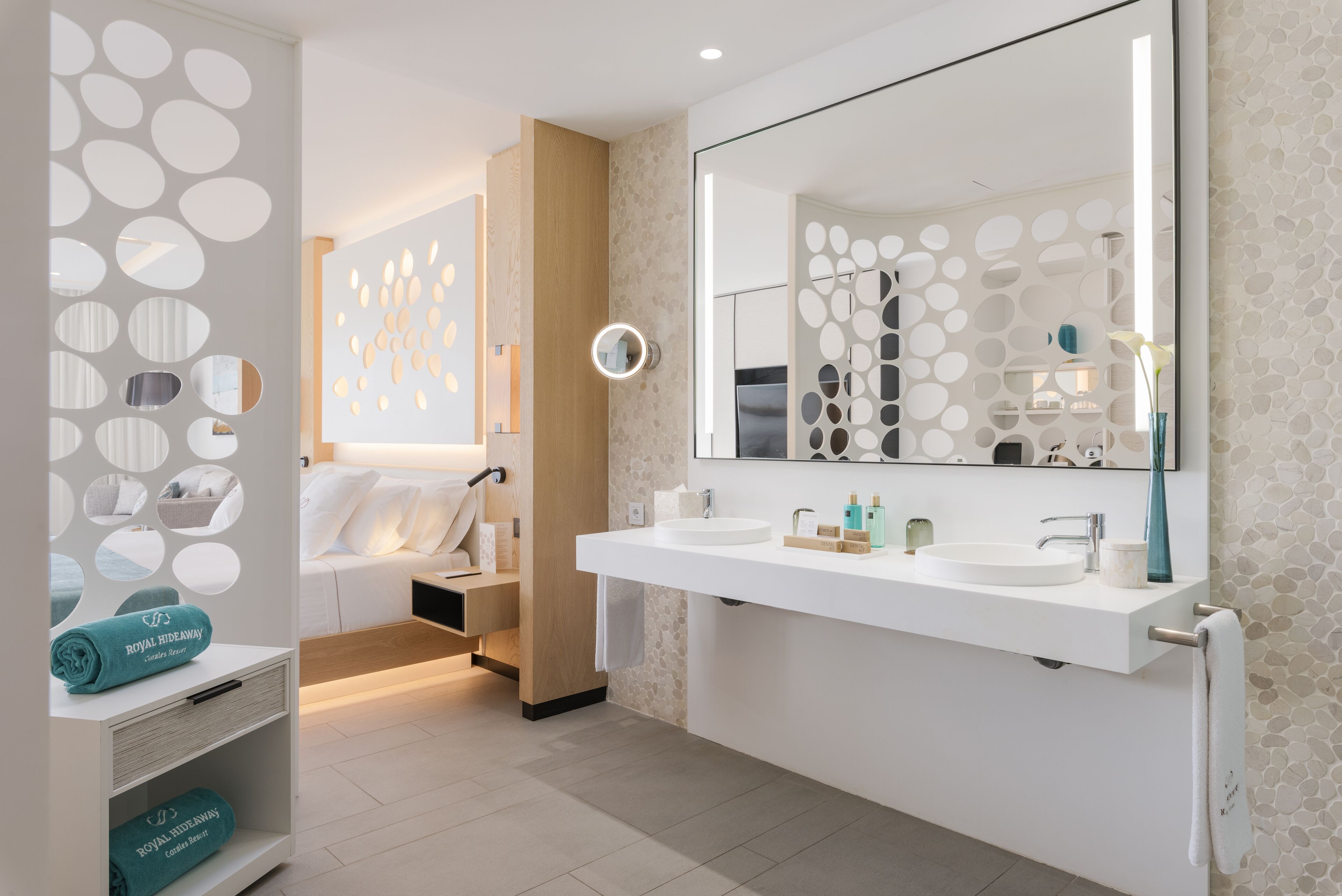 Un baño moderno con un espejo grande, dos lavamanos y un perchero para toallas.