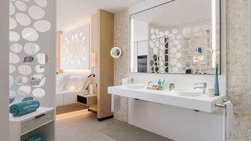 Un baño moderno con un espejo grande, dos lavamanos y un perchero para toallas.