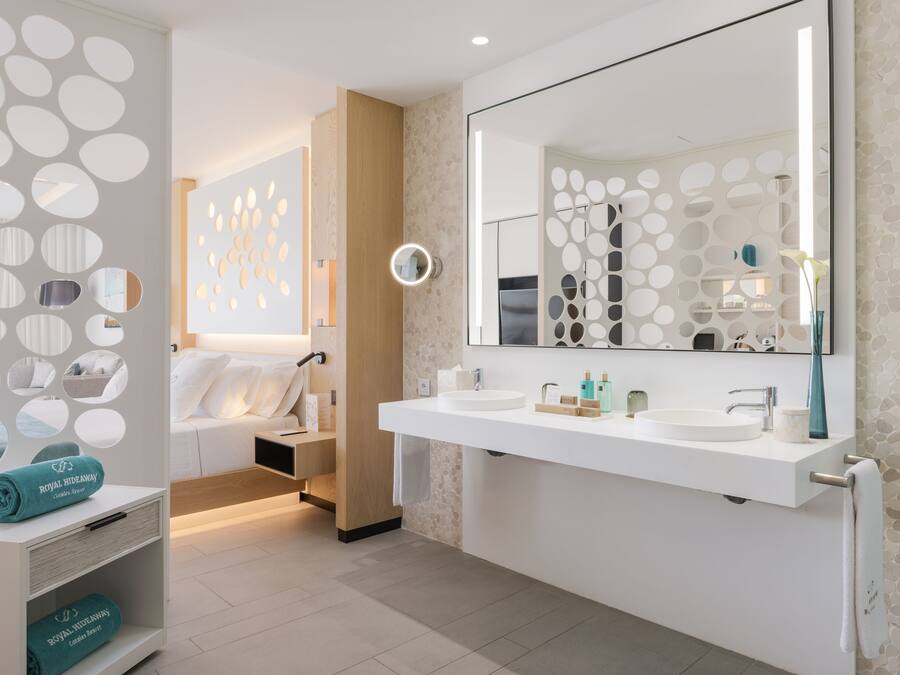 Un baño moderno con un espejo grande, dos lavamanos y un perchero para toallas.