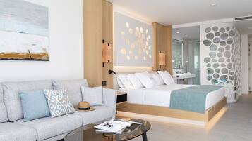 A modern hotel room with a sofa, a bed, a glass coffee table, and a wall with circular patterns.