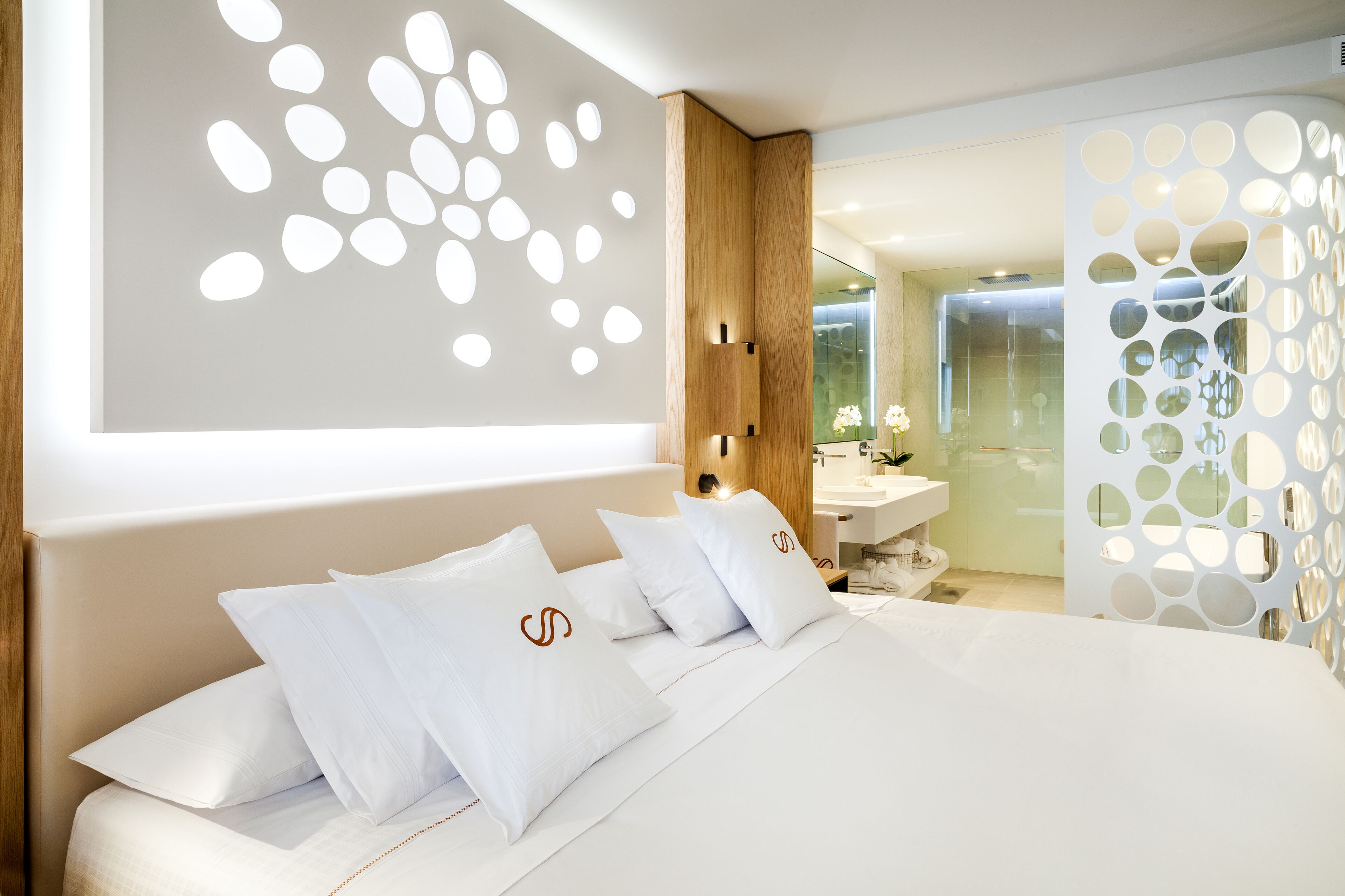 A modern bedroom with a large bed, white bedding, and a wooden headboard.