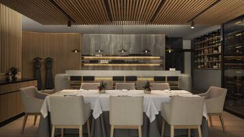 A modern dining area with a long table, cushioned chairs, and a central bar area with shelves.