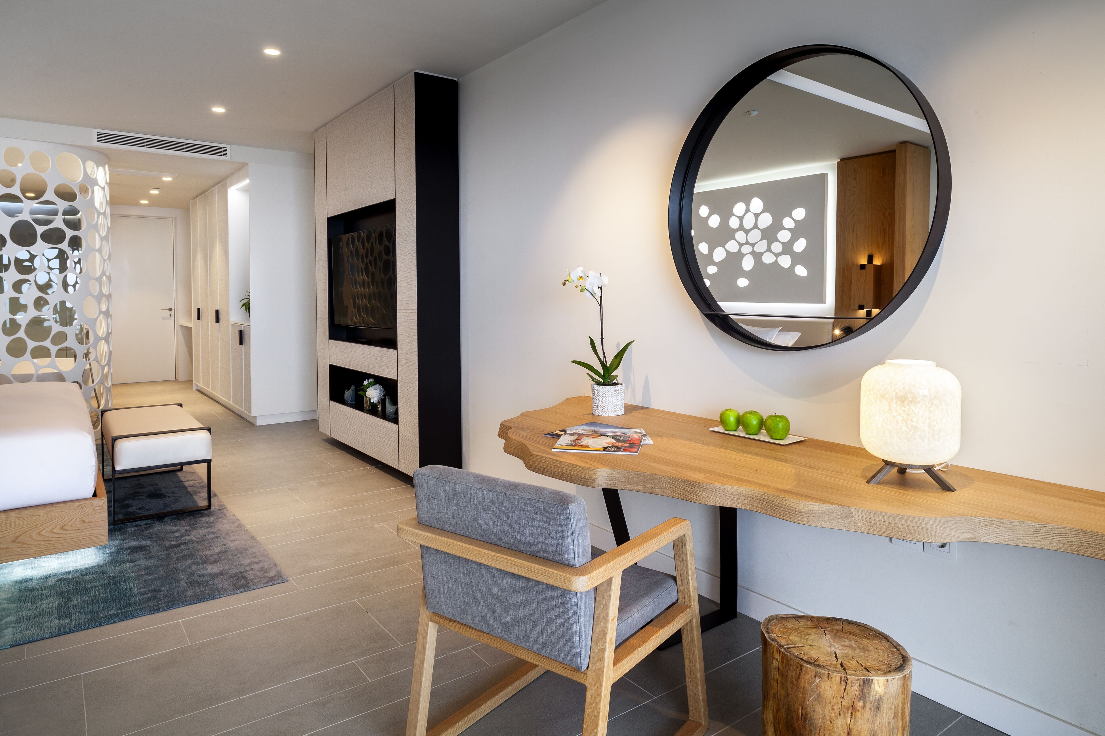 Una sala moderna con una mesa de comedor de madera, un espejo redondo y una silla tapizada de color gris.