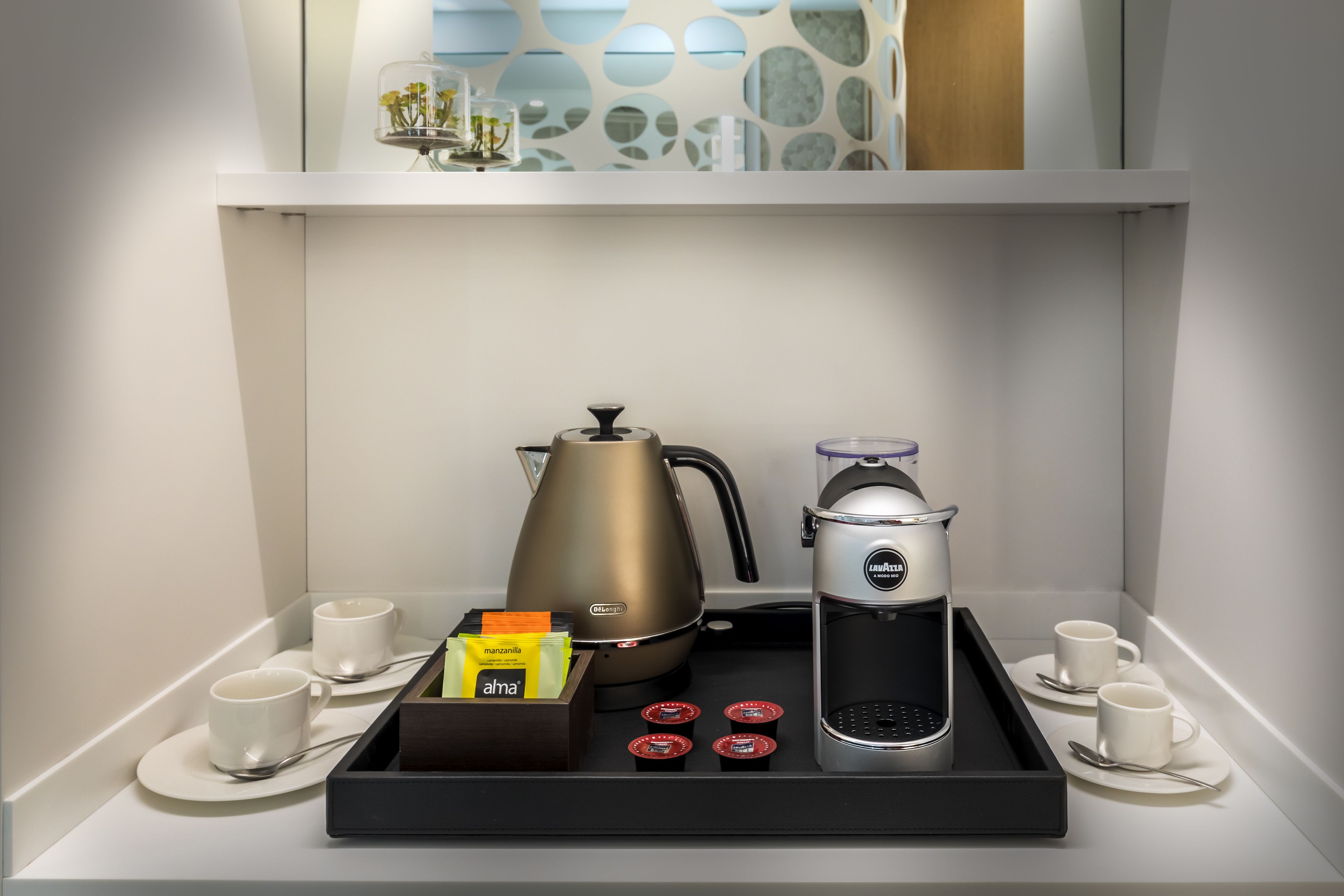 Eine Kaffeestation mit Kaffeemaschine, Kaffeemühle, Tassen und Kaffeekapseln.