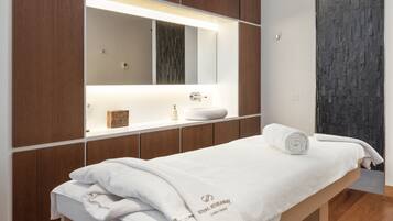 A modern bathroom with a wooden vanity, a large mirror, and a white towel on a bench.