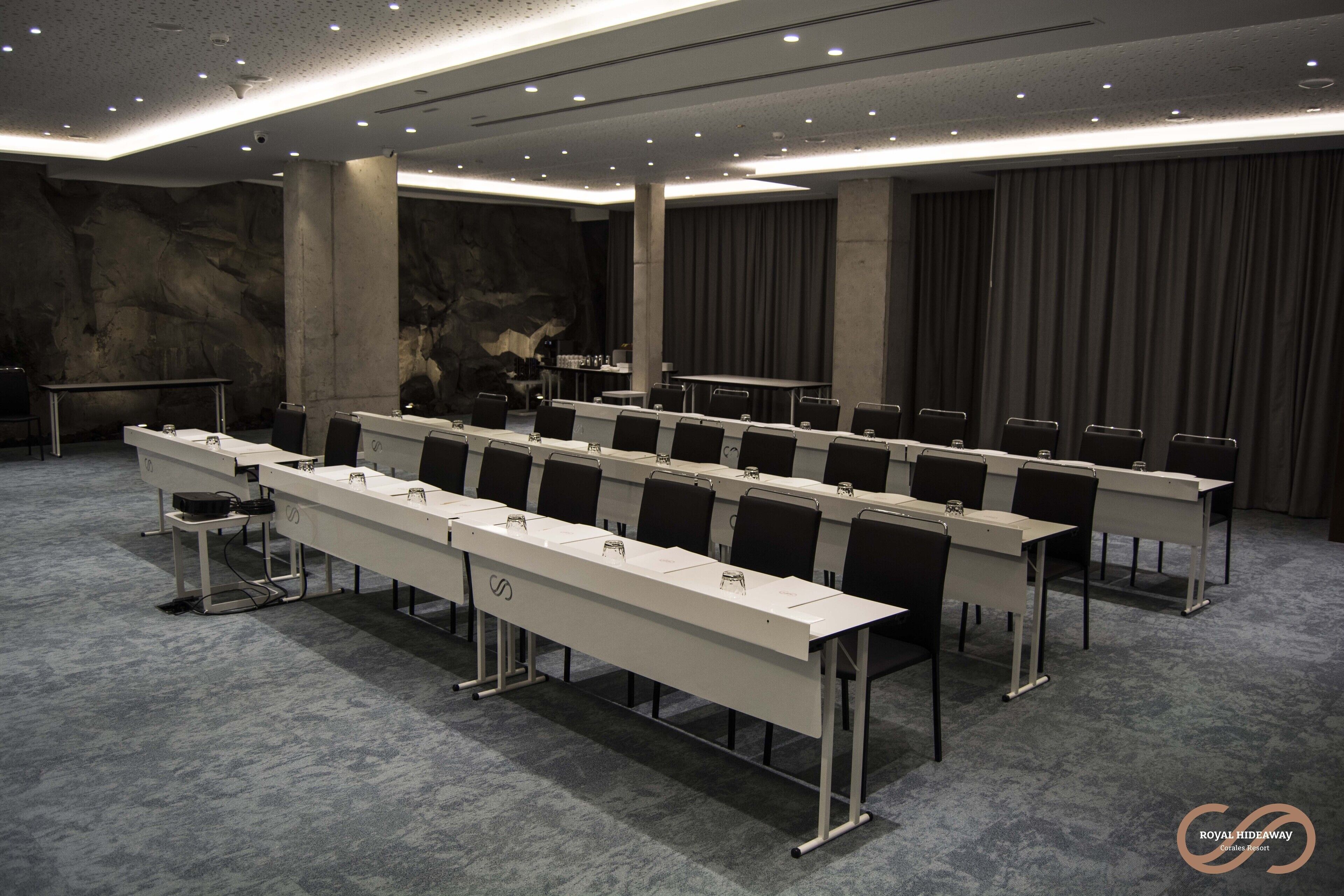 A conference room with long tables, chairs, and a stage.