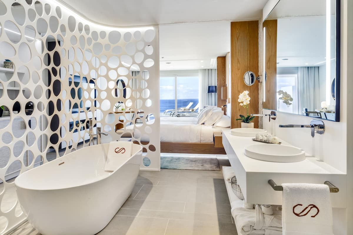 A modern bathroom with a freestanding bathtub, a double sink vanity, and a large mirror.