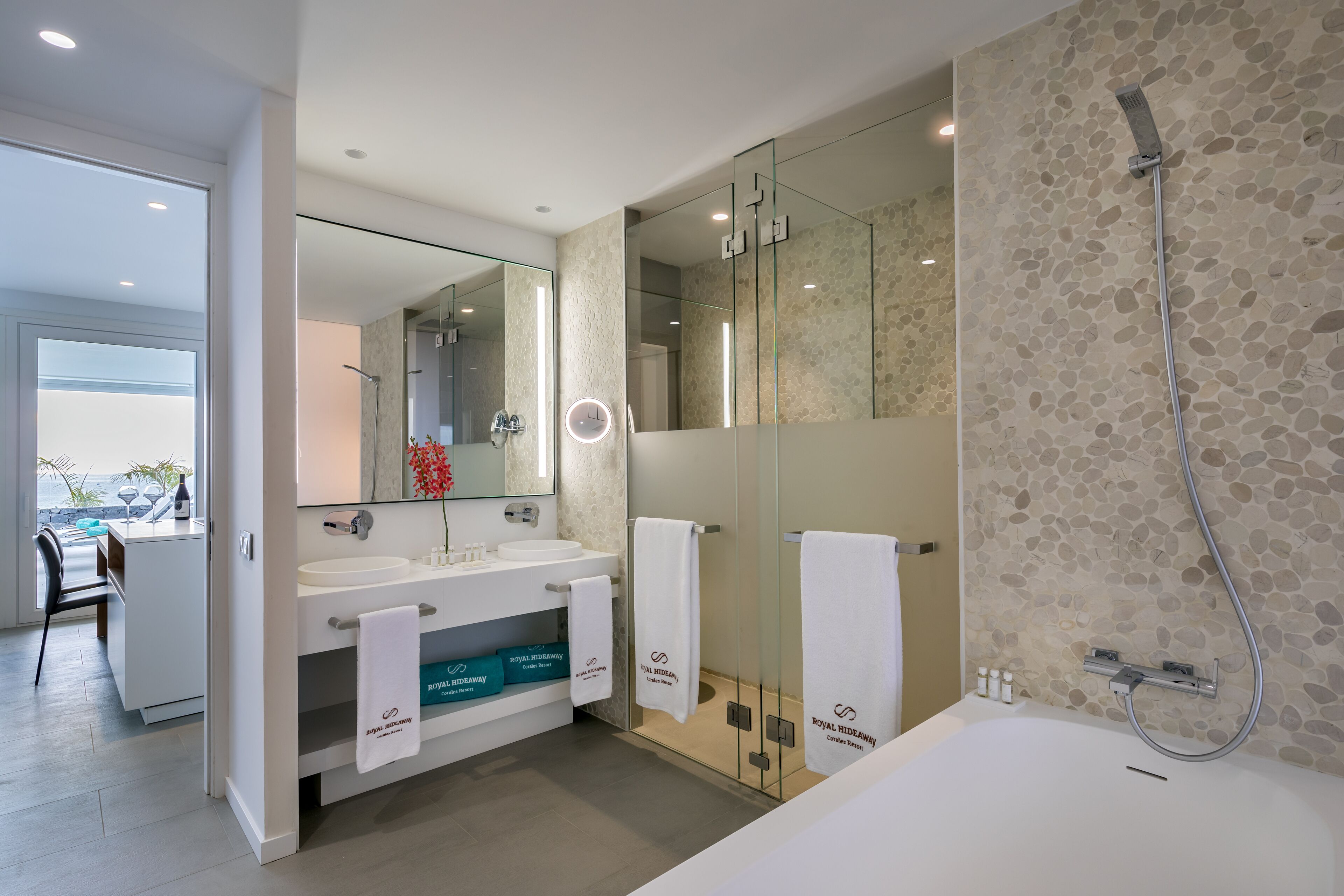 A modern bathroom with two sinks, a large mirror, a shower, and a bathtub.