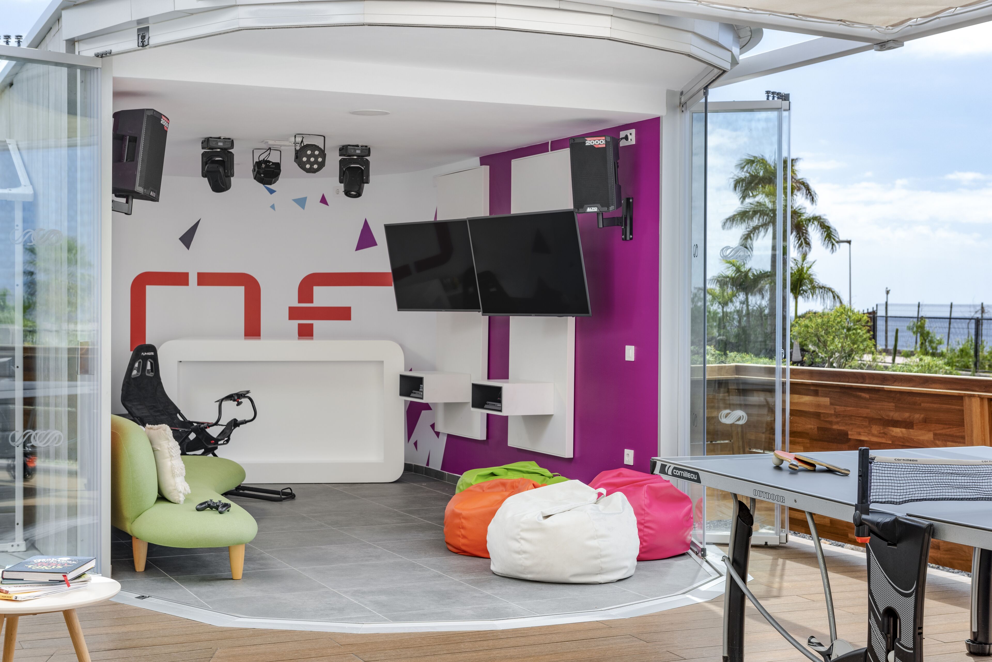 A modern room with a white and purple color scheme, a mounted TV, a bike, and a ping pong table.
