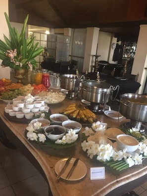 A buffet setup with various food items, including fruits, vegetables, and multiple serving dishes.
