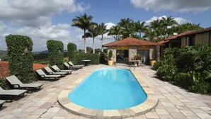 A swimming pool with lounge chairs, surrounded by palm trees and a clear sky.