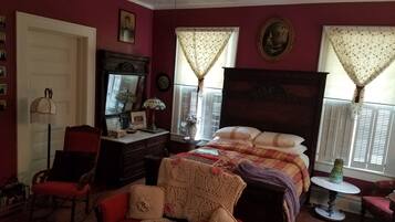 Un dormitorio con una cama grande, un aparador, una silla y una mesita.