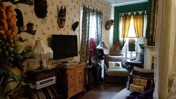 A living room with a television, decorative wall art, a sofa, and a lamp.