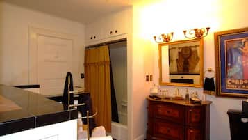 A bathroom with a shower, a vanity with a mirror, and a framed picture on the wall.
