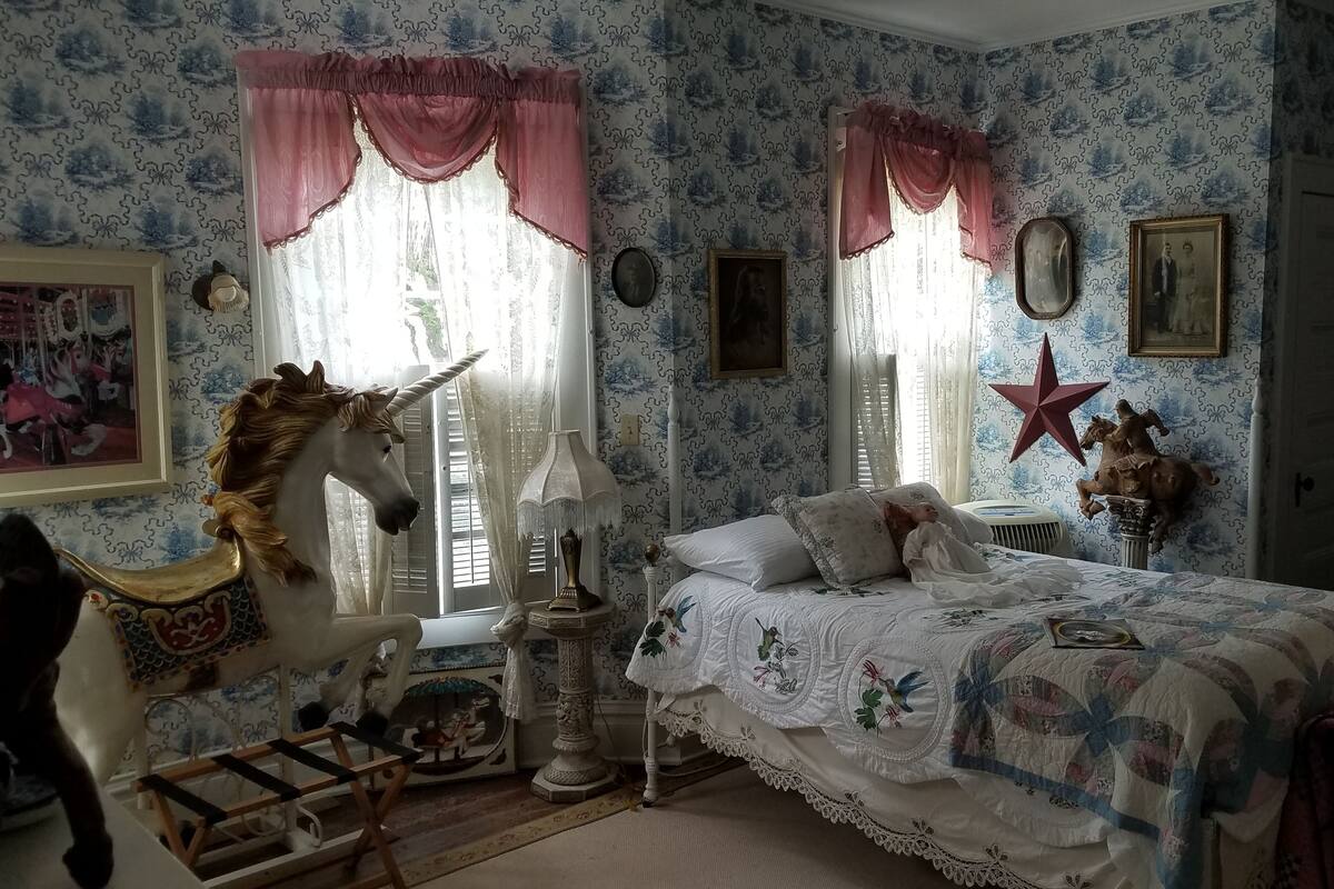 A bedroom with a bed, a unicorn chair, a lamp, and a star decoration.