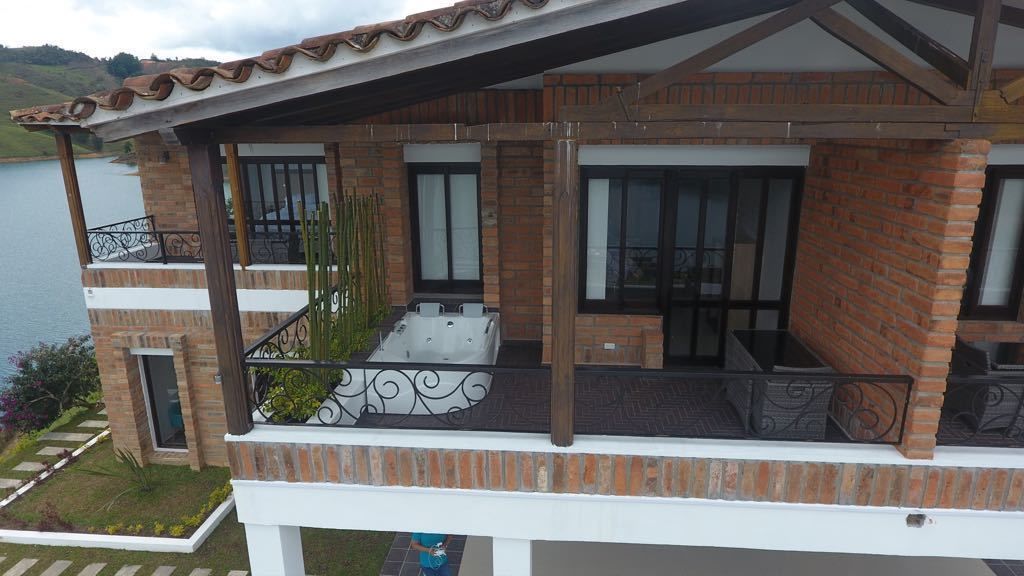 A two-story building with a balcony, large windows, and a view of a body of water.