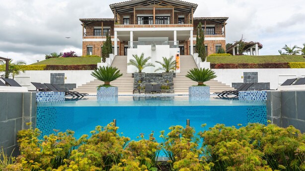 A modern hotel with a large pool, a covered outdoor area, and a staircase leading to the entrance. - Hotel La Magdalena (El Peñol)