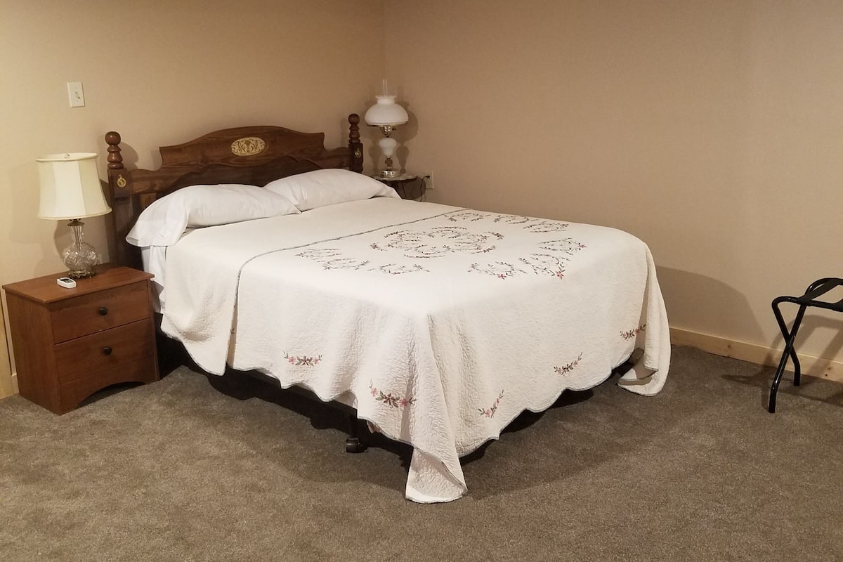 Une chambre à coucher avec un lit double, deux tables de chevet, une lampe et une chaise.