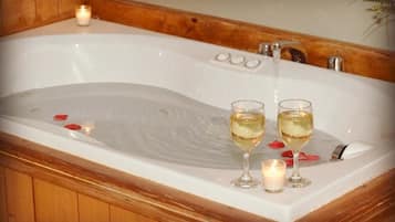 Une baignoire, deux verres de vin blanc, une bougie et des pétales de rose.