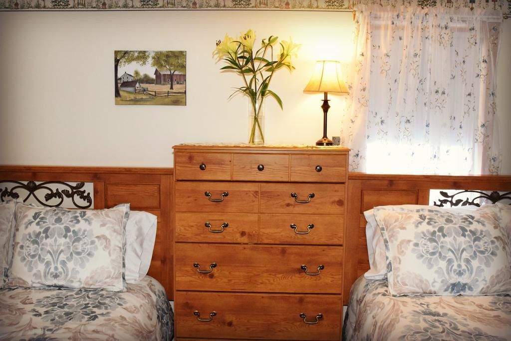 Un dormitorio con dos camas, un aparador de madera, una lámpara y un cuadro en la pared.