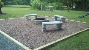 A fire pit area with benches and a stone structure. - Beagle's Bed & Breakfast (Paxinos)