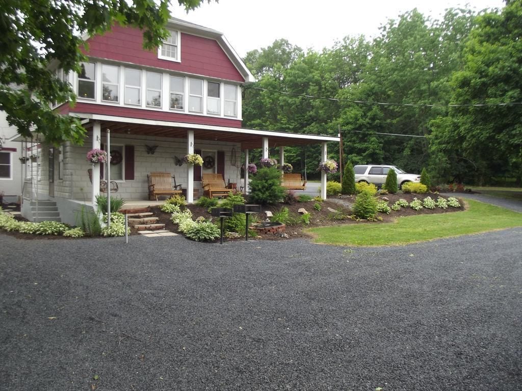 A two-story house with a porch, a covered front entrance, and a gravel driveway.