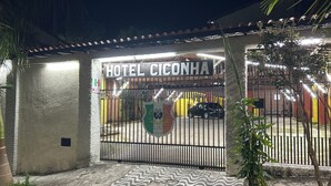 Una entrada porticada al Hotel Ciconha, con un portón metálico, un camino de entrada pavimentado y un felpudo pequeño.