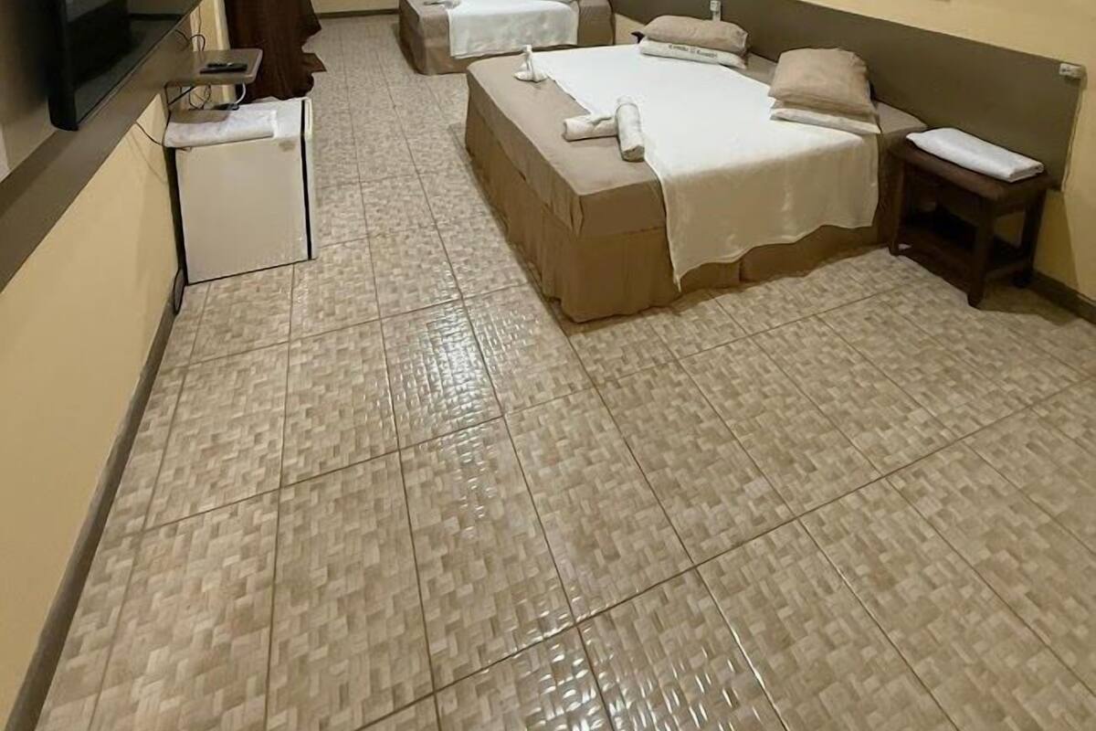 A hotel room with two beds, a TV, a small table, and a wall-mounted picture.
