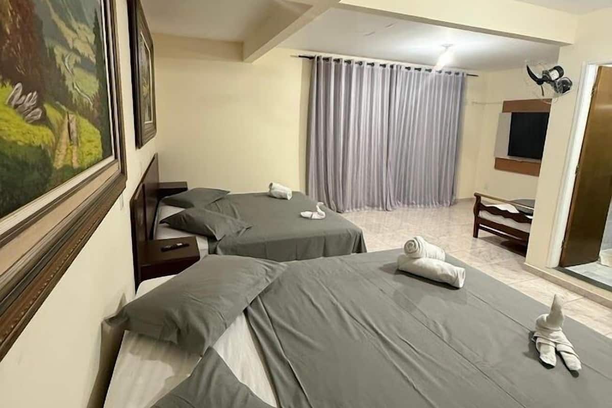 A hotel room with two beds, a desk, a chair, a window with curtains, and a painting on the wall.