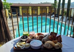 Una mesa de comedor con diversos alimentos y vista a una piscina.