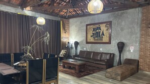 Una sala de estar con techo de madera, un sofá de cuero marrón, una mesa de comedor con sillas y un cuadro grande en la pared.