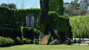 A building with a tower covered in ivy, surrounded by a well-maintained lawn and a bicycle parked nearby.