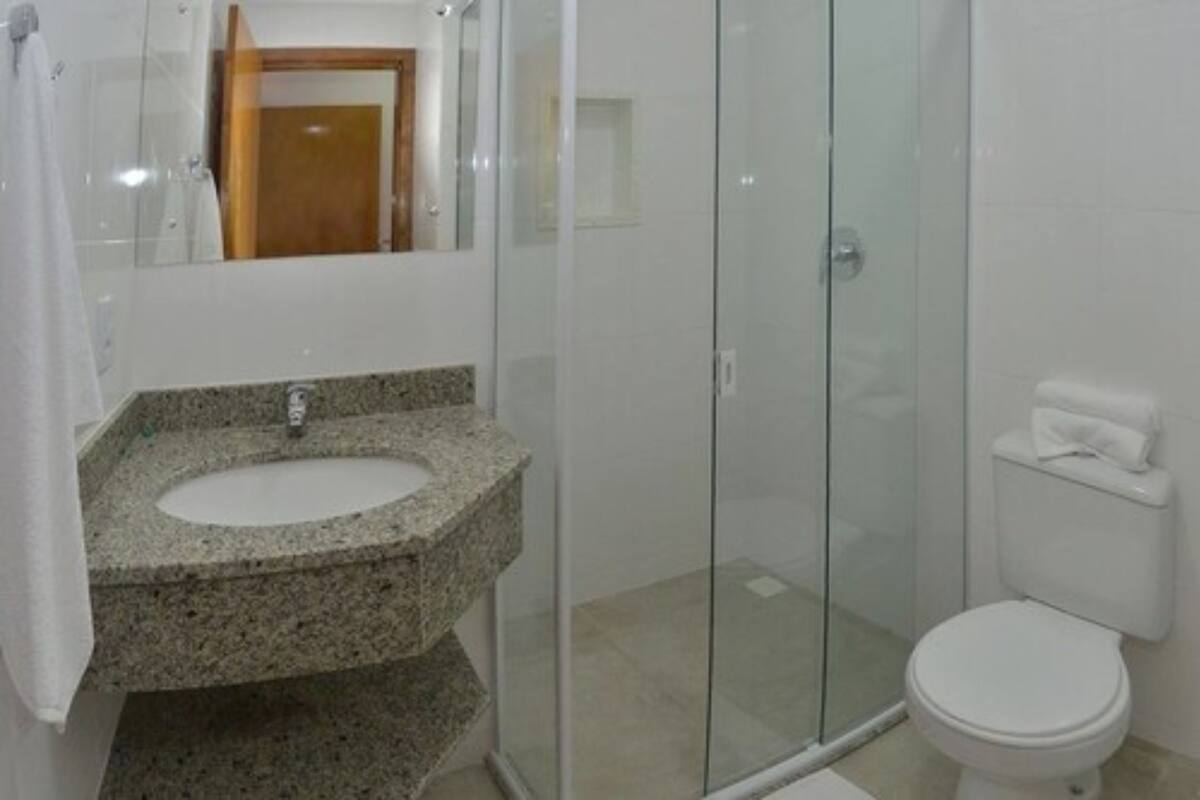 A bathroom with a granite sink, a glass shower enclosure, and a white toilet.