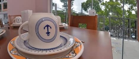 Una mesa con un juego de té, tetera y platillo, sobre un mantel con diseño náutico.