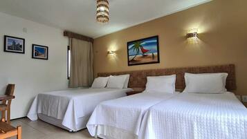 Habitación de hotel con dos camas, un escritorio y una silla. Hay luces de pared y cuadros enmarcados en las paredes.