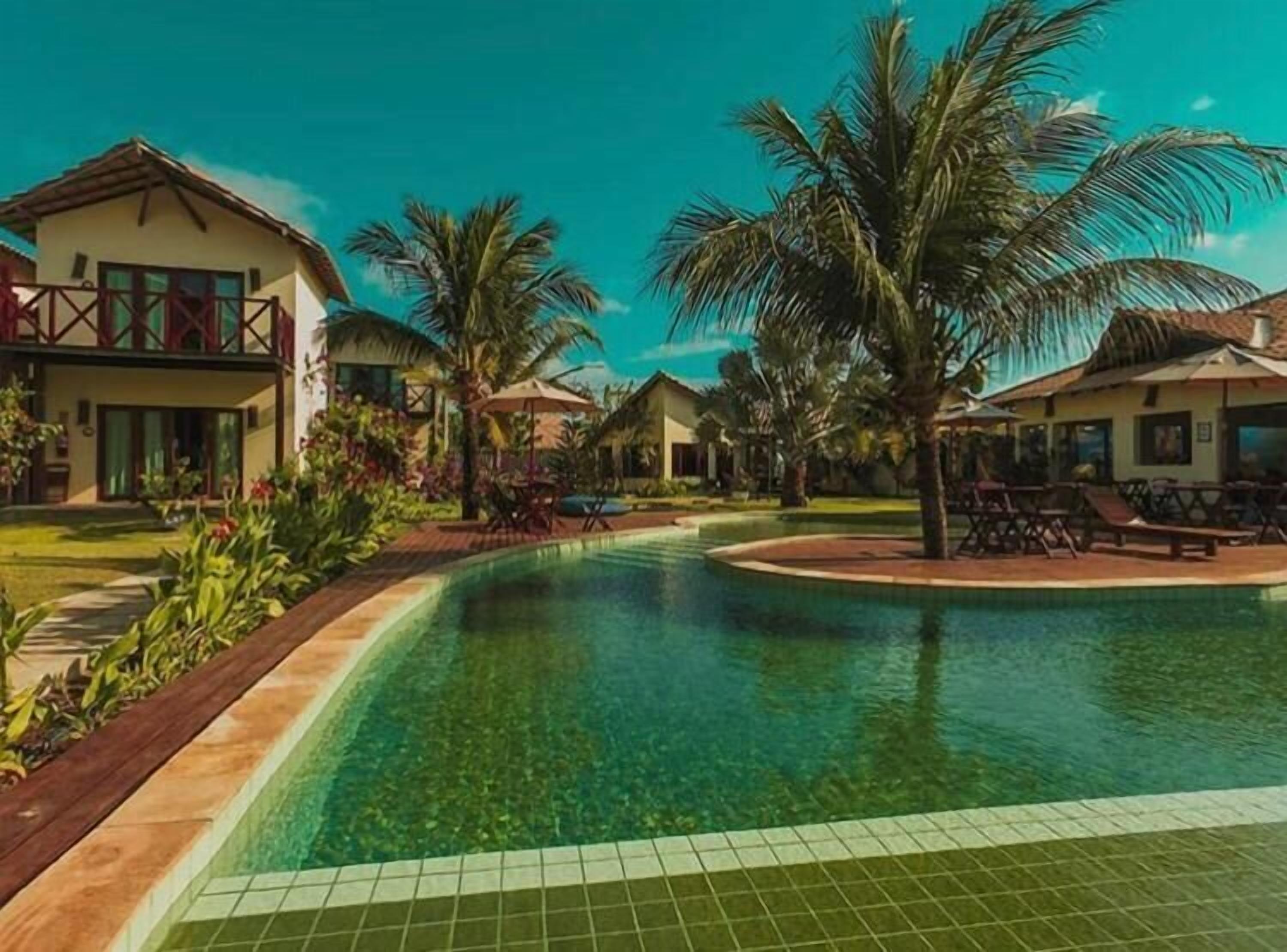 Un resort con piscina, palmeras y un cielo azul despejado.