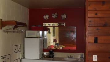 A compact kitchen with a microwave, coffee maker, and sink.