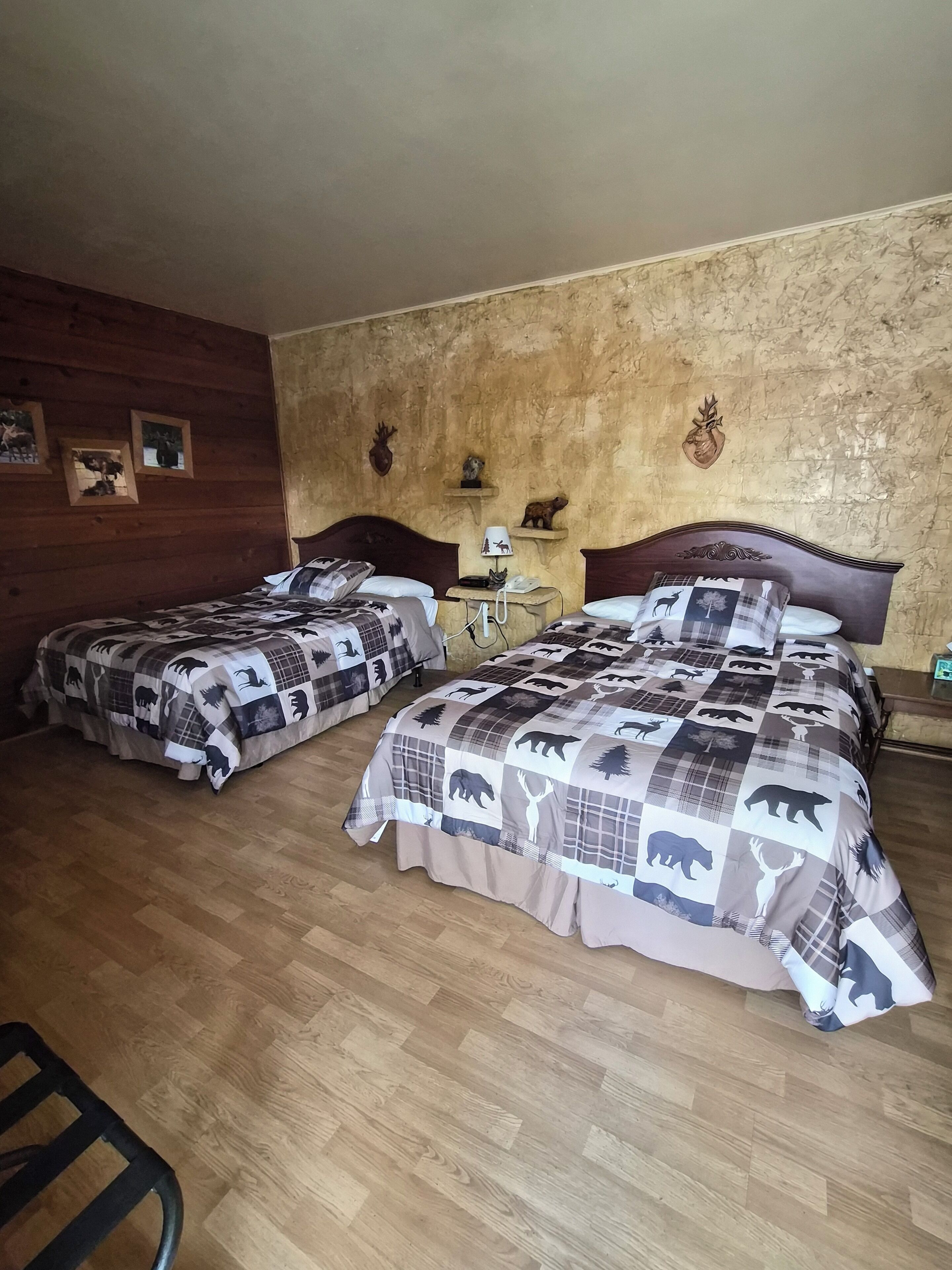 A room with two beds, wooden walls, and a wooden floor.