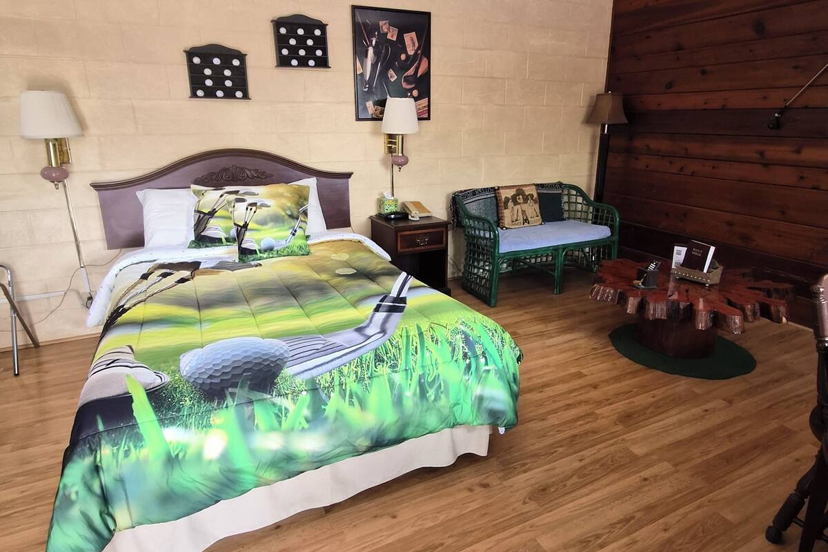 A bedroom with a bed, bedside tables, a chair, a wooden wall, and a lamp.