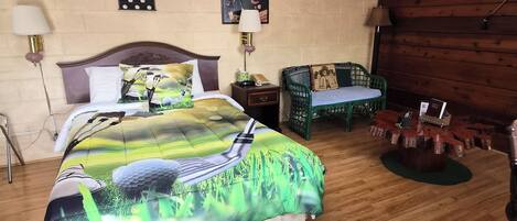 A bedroom with a bed, bedside tables, a chair, a wooden wall, and a lamp.