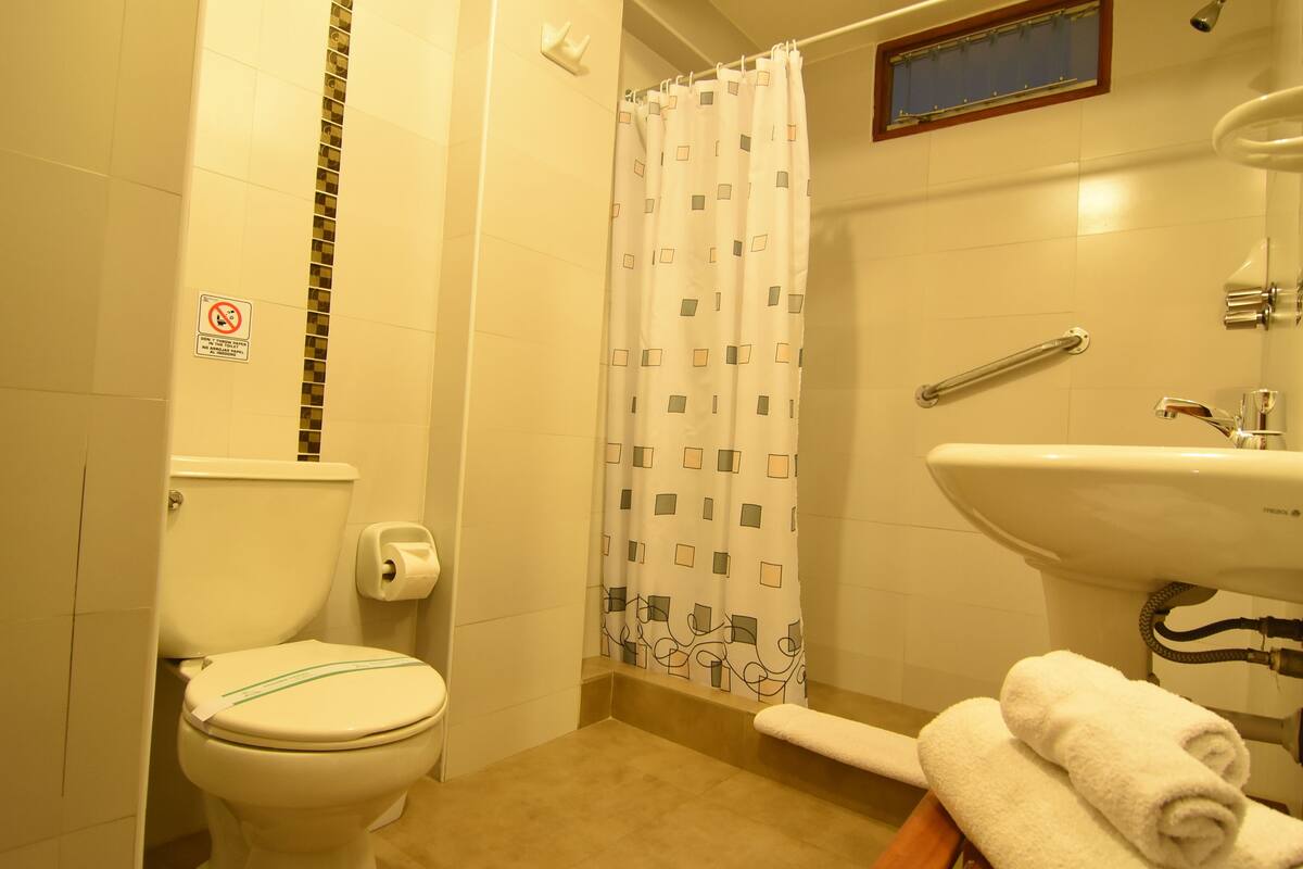 A bathroom with a toilet, shower curtain, sink, and towels.