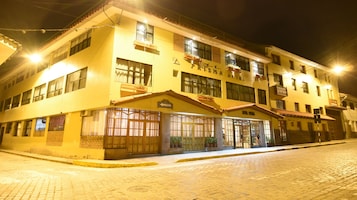 Un hotel con fachada amarilla, múltiples ventanas y un letrero que indica un restaurante.