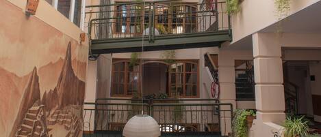 A multi-level atrium with glass ceilings, balconies with plants, and a mural on the lower wall.