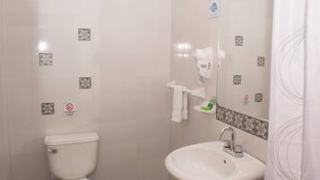 Un baño con inodoro, lavamanos y cortina de ducha.