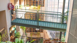 Un atrium à plusieurs niveaux, doté d’une verrière, de nombreux balcons et de plantes en pot.