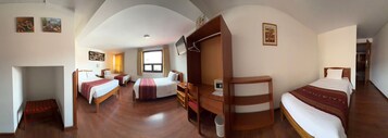 Habitación de hotel con dos camas individuales, un escritorio, una silla y un armario.