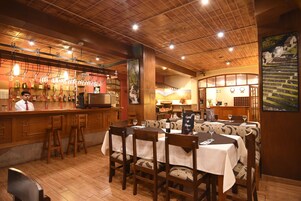 Un restaurante con interiores de madera, una zona de bar y mesas de comedor con sillas.