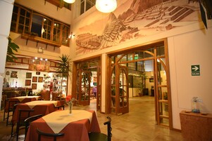 Un restaurante con varias mesas, un mural en la pared y un letrero que indica la salida.