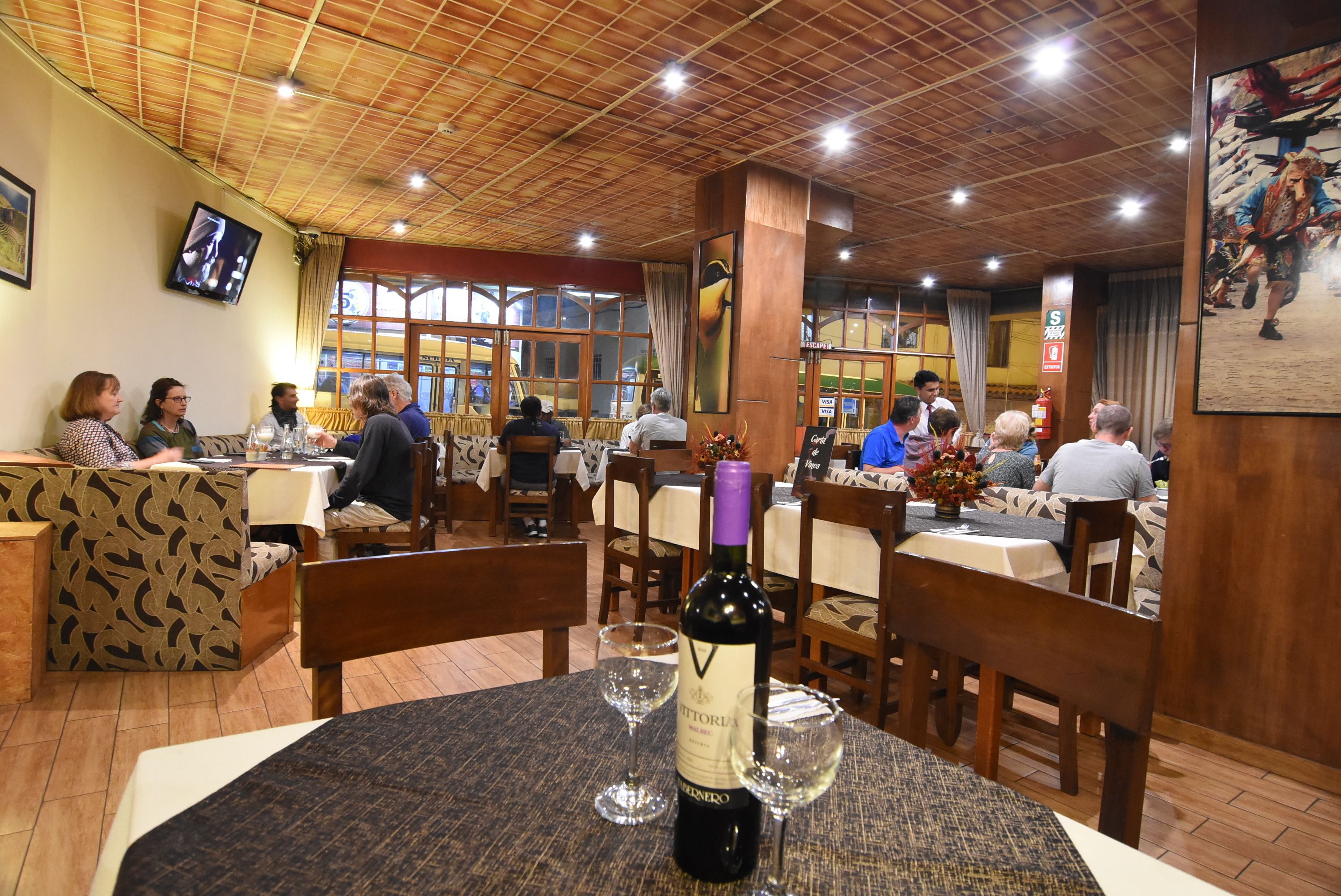 A restaurant with wooden ceiling and tables set for dining.